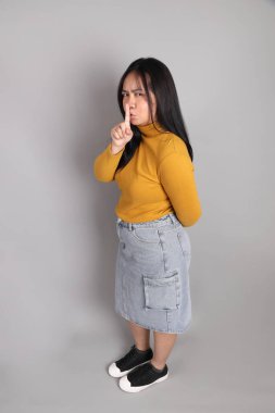 Güneydoğu Asyalı kadının üstten görünüşü. Gri arka planda tam boy giyinmiş, günlük sarı giyinmiş..