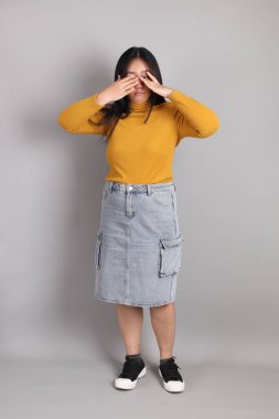 Gri arka planda duran Güneydoğu Asyalı kadının boyu.