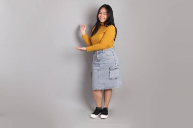 Gri arka planda duran Güneydoğu Asyalı kadının boyu.