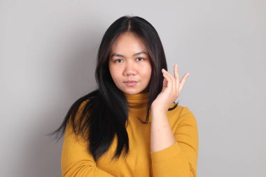 Gri el işaretinin üzerinde duran Güneydoğu Asya 'lı yetişkin kadın..