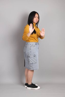 Gri arka planda duran Güneydoğu Asyalı kadının boyu.