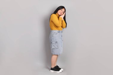 Gri arka planda duran Güneydoğu Asyalı kadının boyu.