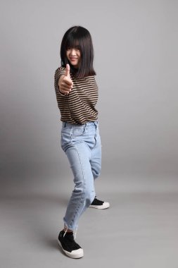 Gri arka planda duran genç, yetişkin Asyalı kadın..