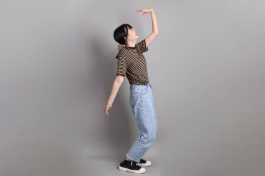 Gri arka planda duran genç, yetişkin Asyalı kadın..