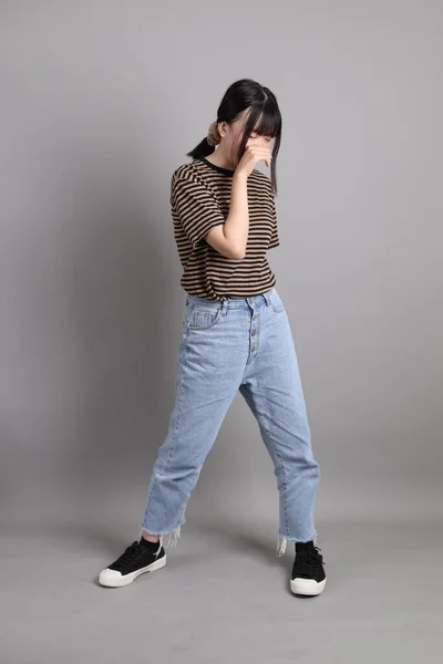 stock image The full length of young adult Asian woman standing on the grey background.