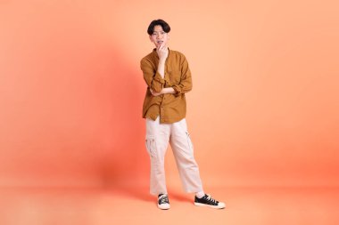 Pembe ya da turuncu arka planda diş telleri olan Doğu Asyalı yetişkin adam..