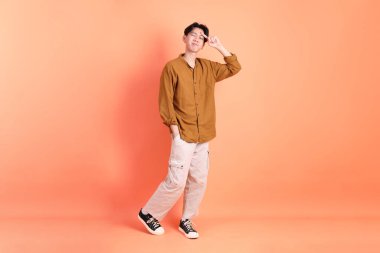 Pembe ya da turuncu arka planda diş telleri olan Doğu Asyalı yetişkin adam..