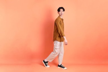 Pembe ya da turuncu arka planda diş telleri olan Doğu Asyalı yetişkin adam..