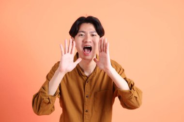 Pembe ya da turuncu arka planda diş telleri olan Doğu Asyalı yetişkin adam..