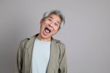 Gri arka planda duran 40 'lı yılların Asyalı, şık, sıradan elbiseli adamı.. 