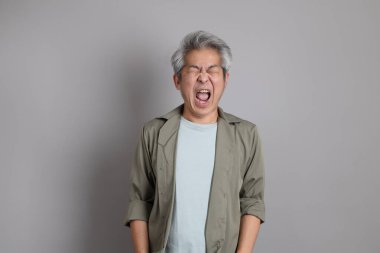 Gri arka planda duran 40 'lı yılların Asyalı, şık, sıradan elbiseli adamı.. 