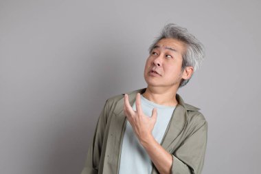 Gri arka planda duran 40 'lı yılların Asyalı, şık, sıradan elbiseli adamı.. 