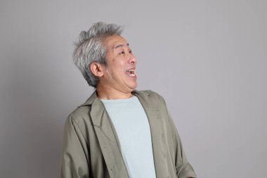 Gri arka planda duran 40 'lı yılların Asyalı, şık, sıradan elbiseli adamı.. 