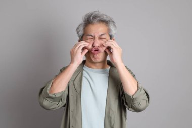 Gri arka planda duran 40 'lı yılların Asyalı, şık, sıradan elbiseli adamı.. 