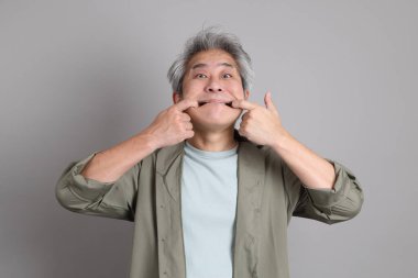 Gri arka planda duran 40 'lı yılların Asyalı, şık, sıradan elbiseli adamı.. 