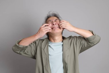 Gri arka planda duran 40 'lı yılların Asyalı, şık, sıradan elbiseli adamı.. 