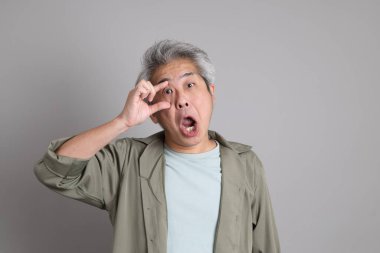 Gri arka planda duran 40 'lı yılların Asyalı, şık, sıradan elbiseli adamı.. 