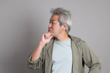 Gri arka planda duran 40 'lı yılların Asyalı, şık, sıradan elbiseli adamı.. 