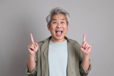 Gri arka planda duran 40 'lı yılların Asyalı, şık, sıradan elbiseli adamı.. 