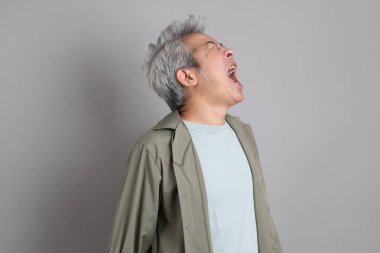 Gri arka planda duran 40 'lı yılların Asyalı, şık, sıradan elbiseli adamı.. 