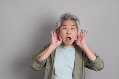 Gri arka planda duran 40 'lı yılların Asyalı, şık, sıradan elbiseli adamı.. 