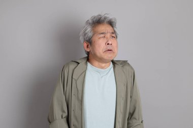 Gri arka planda duran 40 'lı yılların Asyalı, şık, sıradan elbiseli adamı.. 