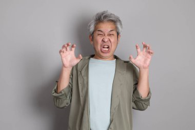 Gri arka planda duran 40 'lı yılların Asyalı, şık, sıradan elbiseli adamı.. 