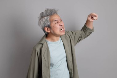 Gri arka planda duran 40 'lı yılların Asyalı, şık, sıradan elbiseli adamı.. 