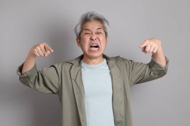 Gri arka planda duran 40 'lı yılların Asyalı, şık, sıradan elbiseli adamı.. 