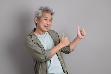 Gri arka planda duran 40 'lı yılların Asyalı, şık, sıradan elbiseli adamı.. 