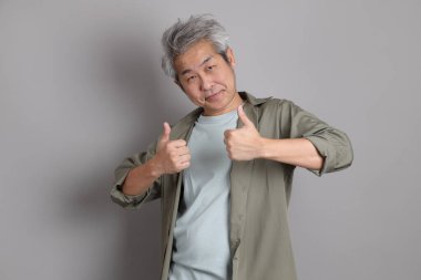 Gri arka planda duran 40 'lı yılların Asyalı, şık, sıradan elbiseli adamı.. 