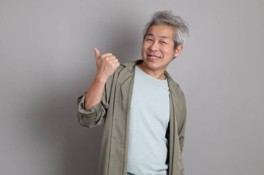 Gri arka planda duran 40 'lı yılların Asyalı, şık, sıradan elbiseli adamı.. 