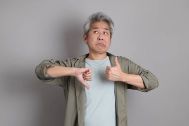 Gri arka planda duran 40 'lı yılların Asyalı, şık, sıradan elbiseli adamı.. 