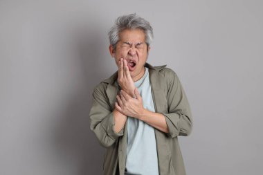 Gri arka planda duran 40 'lı yılların Asyalı, şık, sıradan elbiseli adamı.. 