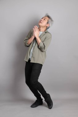 Gri arka planda duran 40 'lı yılların Asyalı, şık, sıradan elbiseli adamı.. 