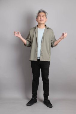 Gri arka planda duran 40 'lı yılların Asyalı, şık, sıradan elbiseli adamı.. 