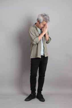 Gri arka planda duran 40 'lı yılların Asyalı, şık, sıradan elbiseli adamı.. 