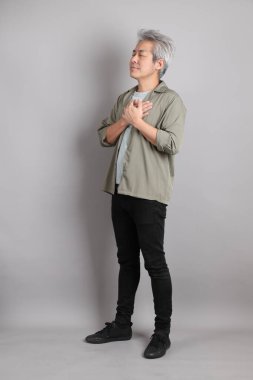 Gri arka planda duran 40 'lı yılların Asyalı, şık, sıradan elbiseli adamı.. 