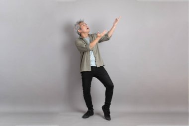 Gri arka planda duran 40 'lı yılların Asyalı, şık, sıradan elbiseli adamı.. 