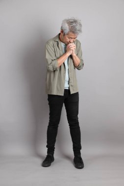 Gri arka planda duran 40 'lı yılların Asyalı, şık, sıradan elbiseli adamı.. 