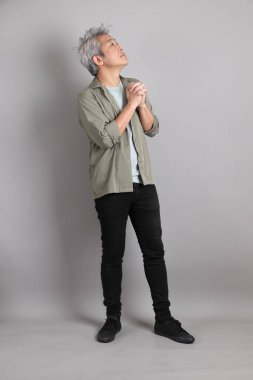 Gri arka planda duran 40 'lı yılların Asyalı, şık, sıradan elbiseli adamı.. 