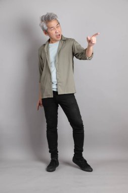 Gri arka planda duran 40 'lı yılların Asyalı, şık, sıradan elbiseli adamı.. 