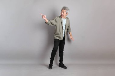 Gri arka planda duran 40 'lı yılların Asyalı, şık, sıradan elbiseli adamı.. 