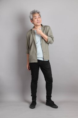 Gri arka planda duran 40 'lı yılların Asyalı, şık, sıradan elbiseli adamı.. 