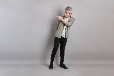 Gri arka planda duran 40 'lı yılların Asyalı, şık, sıradan elbiseli adamı.. 