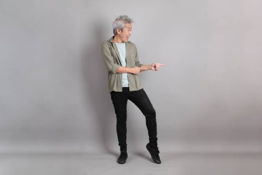 Gri arka planda duran 40 'lı yılların Asyalı, şık, sıradan elbiseli adamı.. 