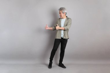 Gri arka planda duran 40 'lı yılların Asyalı, şık, sıradan elbiseli adamı.. 