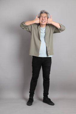 Gri arka planda duran 40 'lı yılların Asyalı, şık, sıradan elbiseli adamı.. 