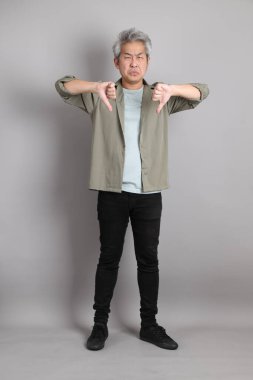 Gri arka planda duran 40 'lı yılların Asyalı, şık, sıradan elbiseli adamı.. 