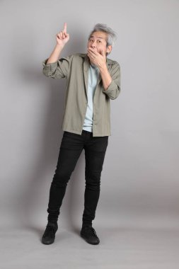 Gri arka planda duran 40 'lı yılların Asyalı, şık, sıradan elbiseli adamı.. 